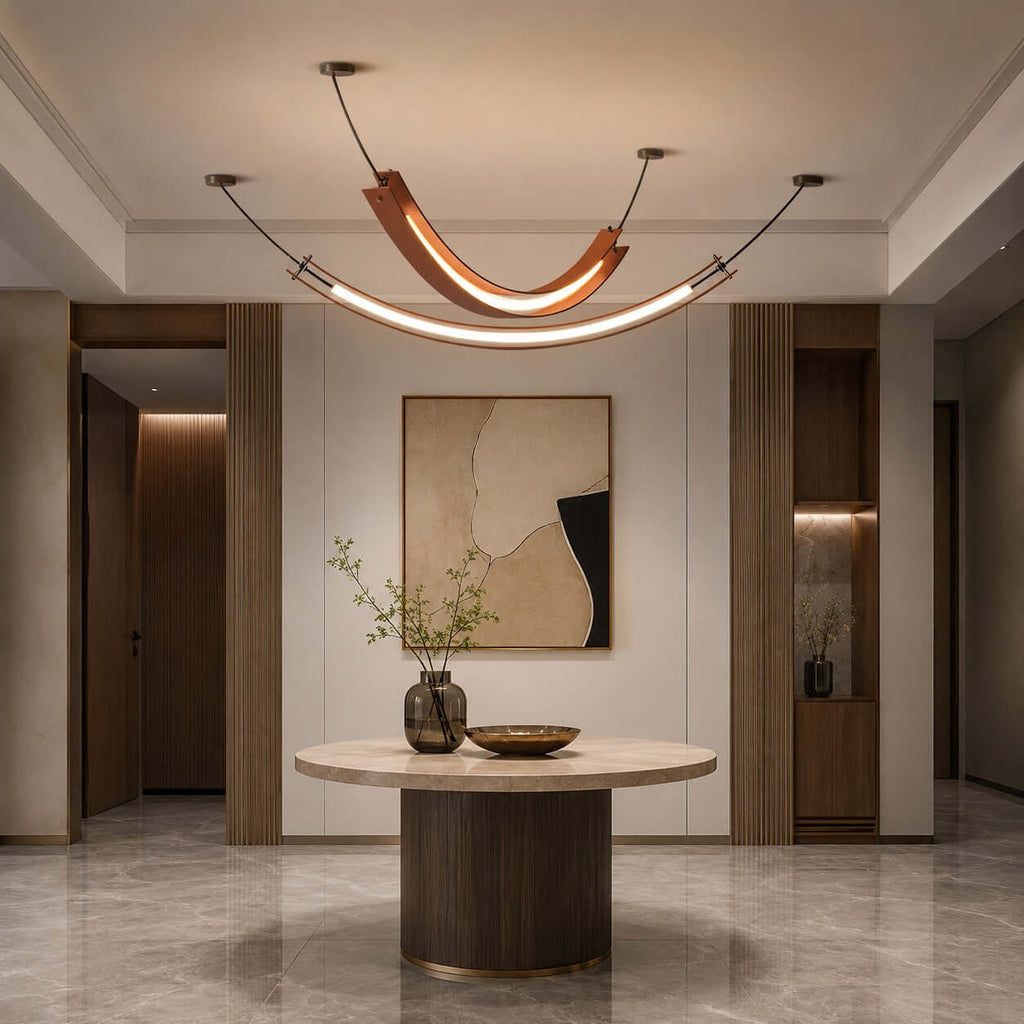 This Clérachic pendant with a lit U-shaped curve and a long strip below hangs in an entrance hall above a round pedestal table.