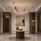 This Clérachic pendant with a lit U-shaped curve and a long strip below hangs in an entrance hall above a round pedestal table.