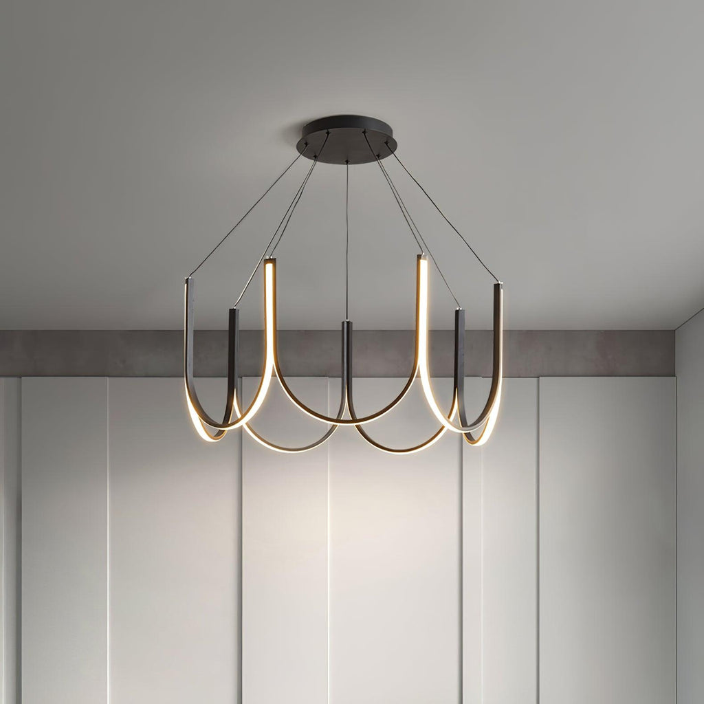 The Clérachic looped arm pendant lit above a pale room, warm light tracing each curve.