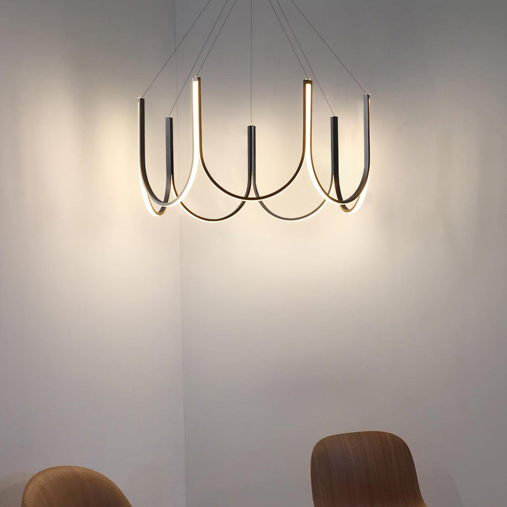 Clérachic looped arm pendant glowing in a cream corner, light washing up the wall.