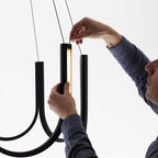 Hands fitting one aluminium U-module into the Clérachic pendant during installation.