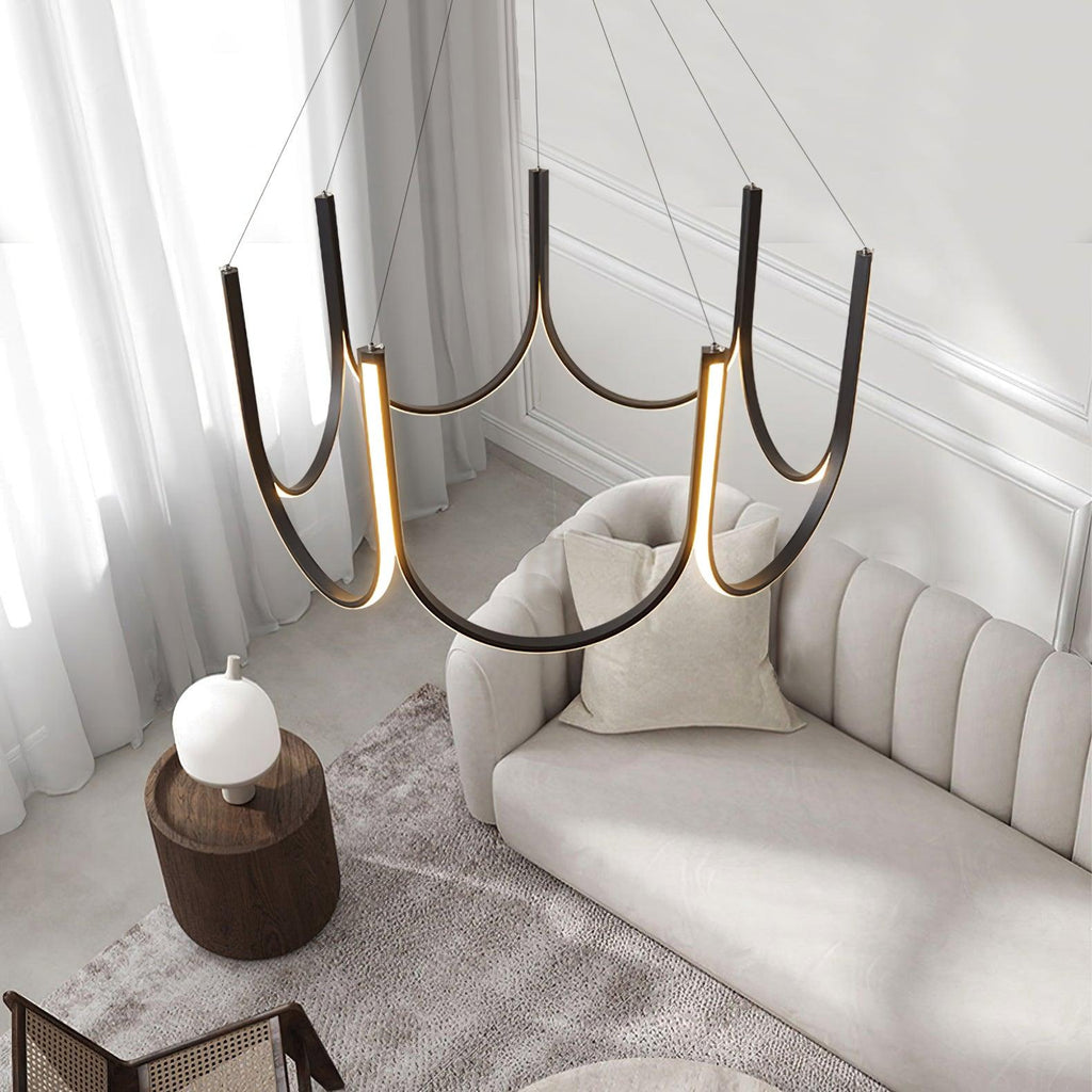 The Clérachic looped arm pendant above a cream sofa, sheer curtains behind it.