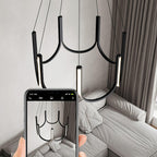 Clérachic looped arm pendant being photographed on a phone above a made bed.