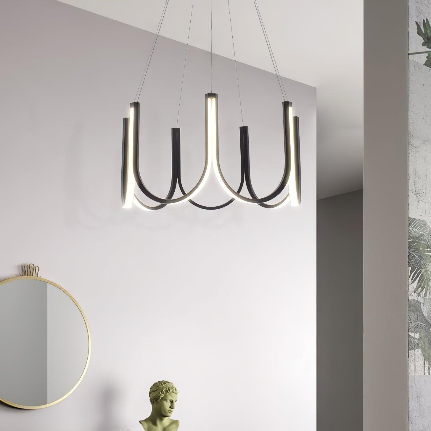 The Clérachic looped arm pendant on a white wall beside a round mirror and plaster bust.