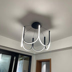 Clérachic looped arm pendant seen close to the ceiling, warm light pooling above it.