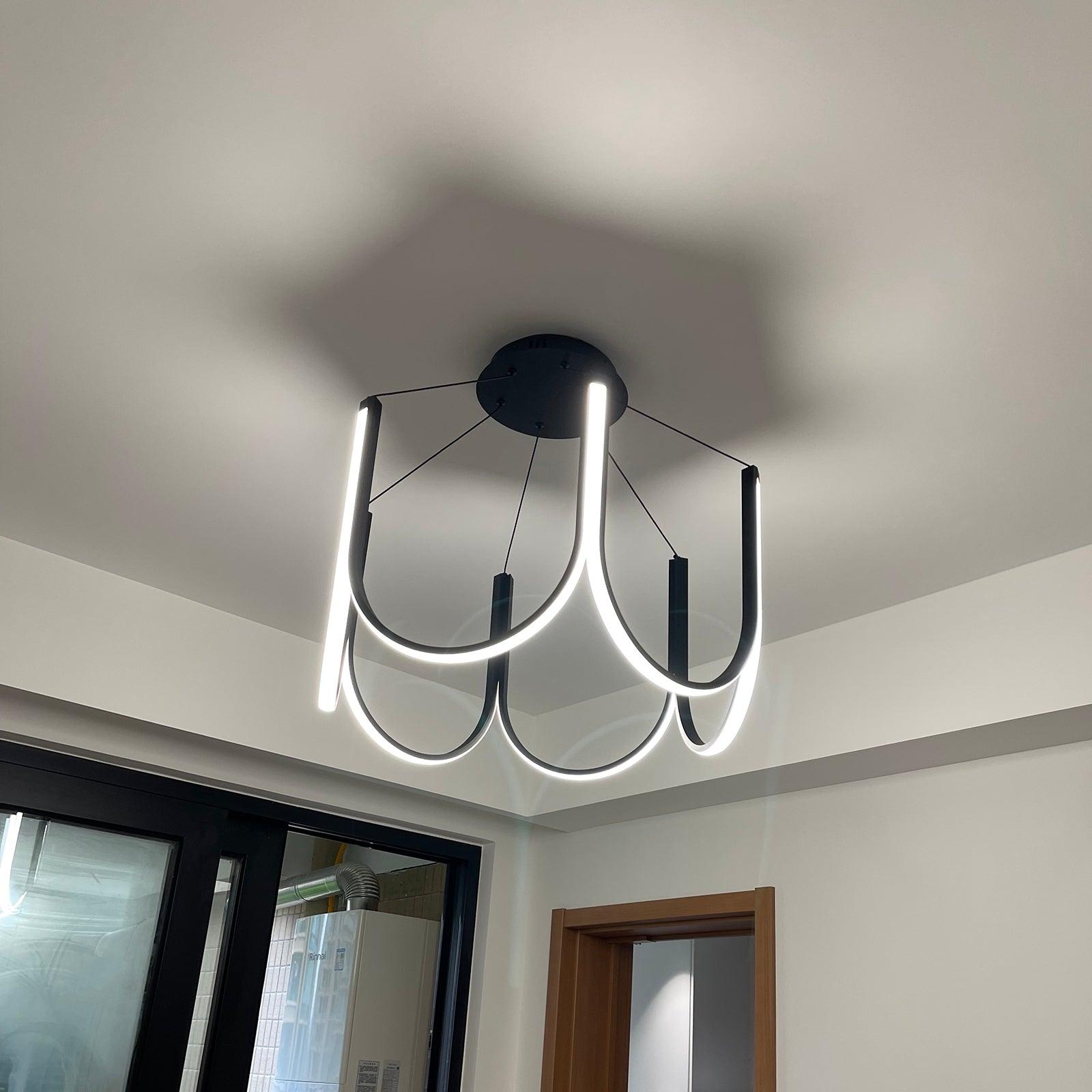 Clérachic looped arm pendant seen close to the ceiling, warm light pooling above it.