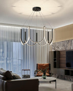 The Clérachic looped arm pendant above a leather sofa in a marble-walled living room.
