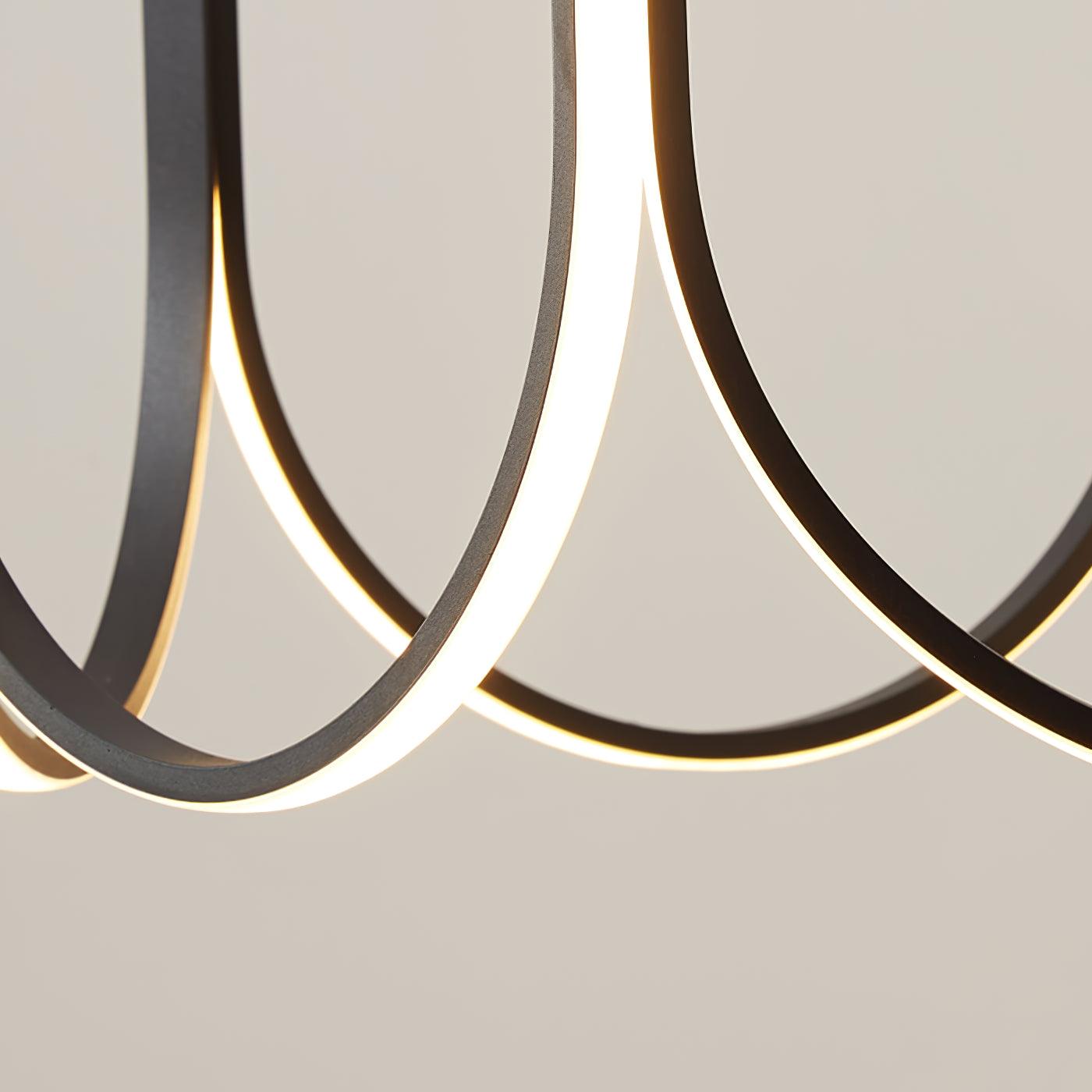 Macro of two Clérachic pendant arms crossing, the lit strip curving through the frame.
