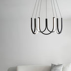 The Clérachic looped arm pendant above a pale sofa against a plain white wall.