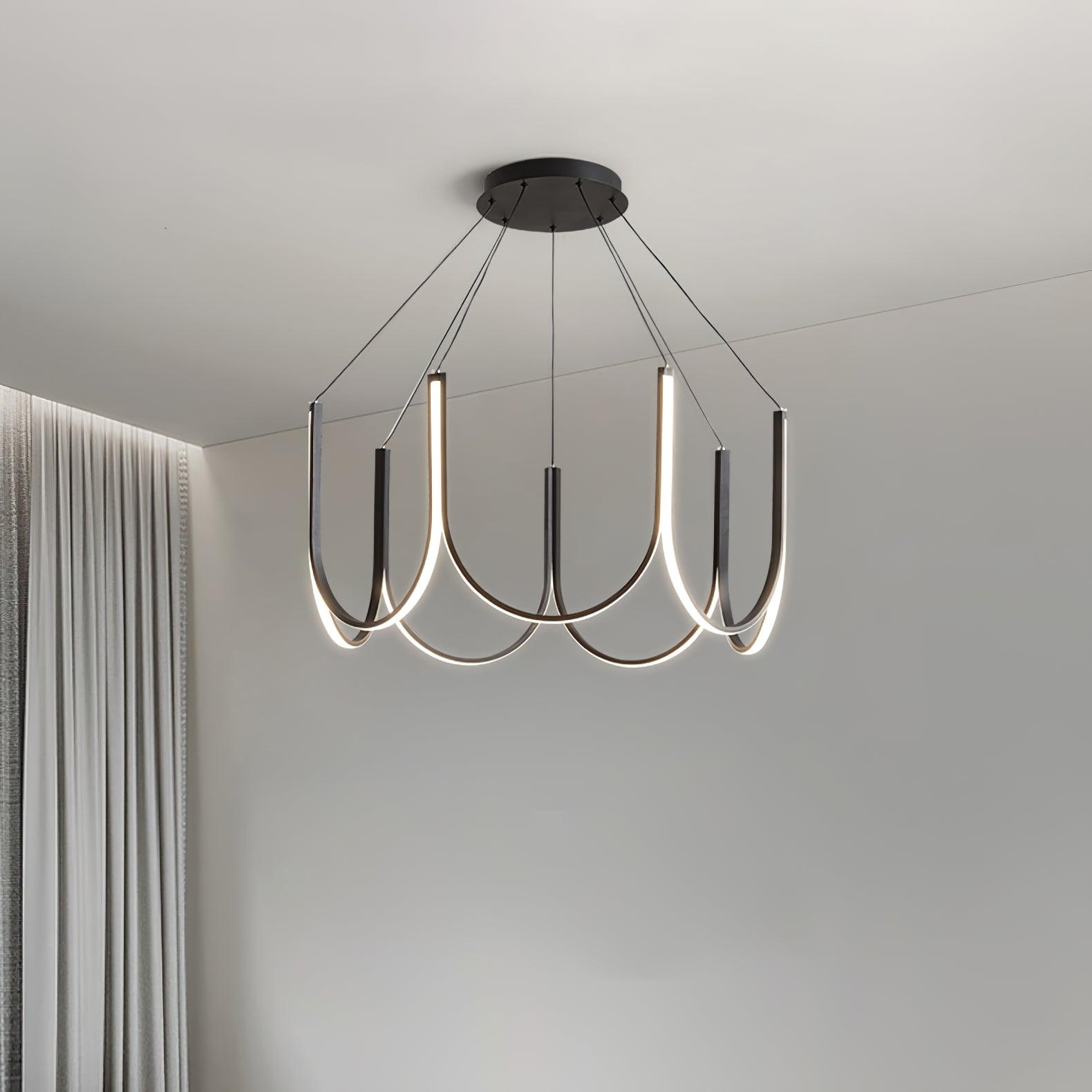 The Clérachic looped arm pendant lit beside pale curtains in a quiet corner.
