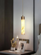 A single Clérachic pendant lights a bedside shelf, its warm beam falling across a framed photo and a small planter.