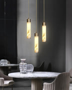 The Clérachic cylinders hang in a dark dining corner above a round marble café table and upholstered chairs.