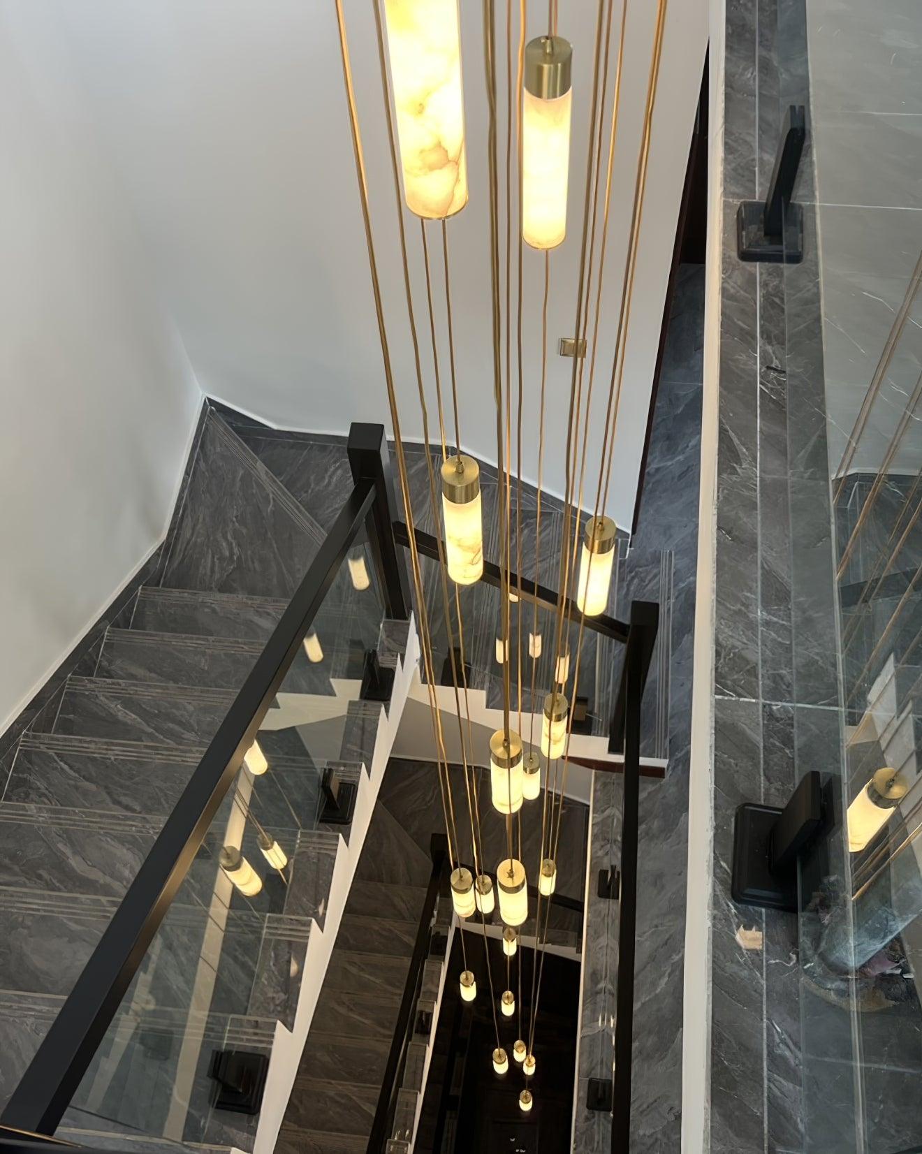 Clérachic pendants at many different drop lengths fill the void of a marble and glass stairwell from top to bottom.