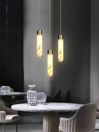 The Clérachic cluster hangs above a marble dining table in a dark panelled corner, three drops at staggered heights.