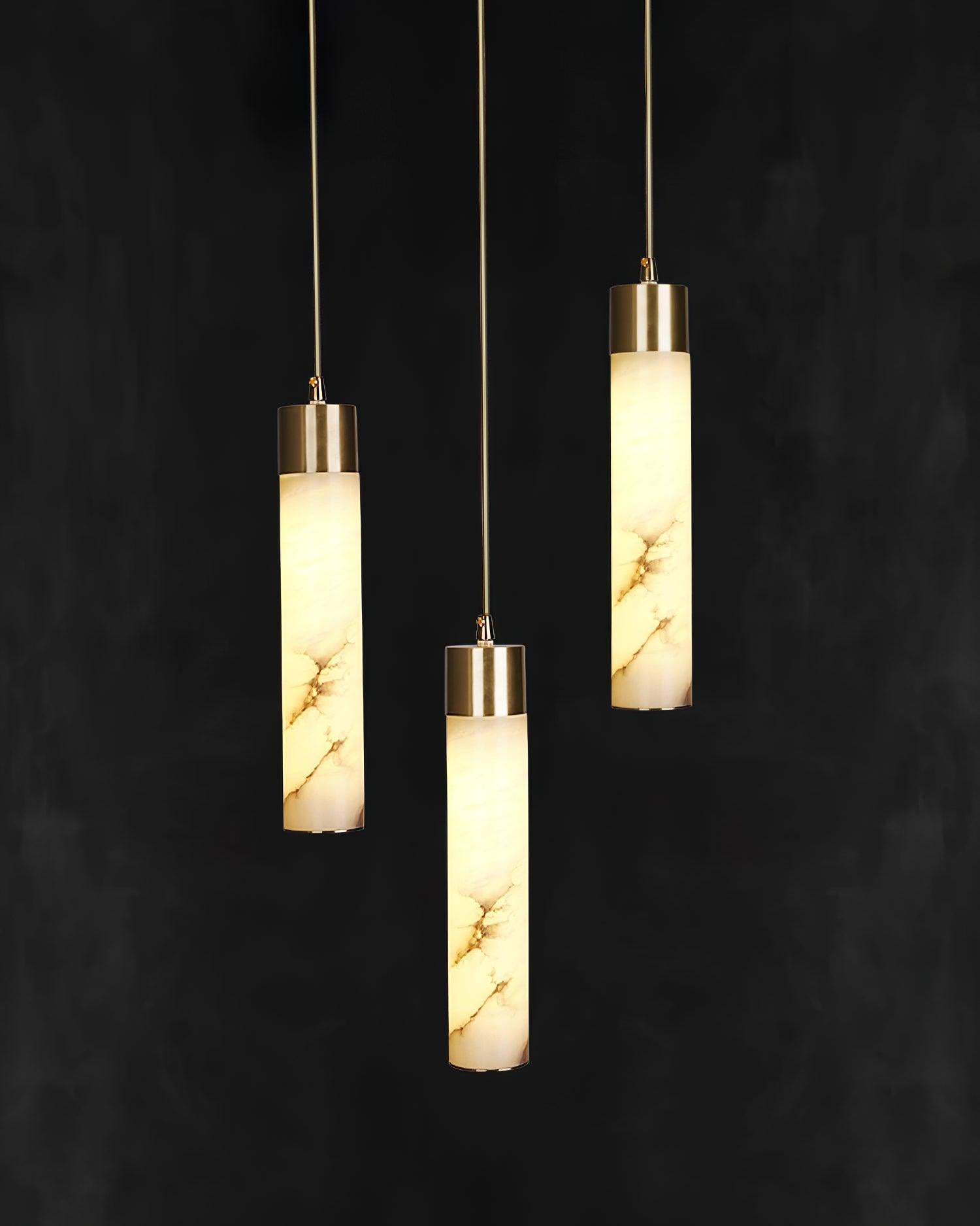 The Clérachic trio lit against near-black, each alabaster tube carrying its own pattern of grey and amber veining.