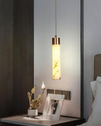Clérachic hangs the pendant low at a walnut-panelled bedside, the alabaster shade lit warm above a framed photograph.