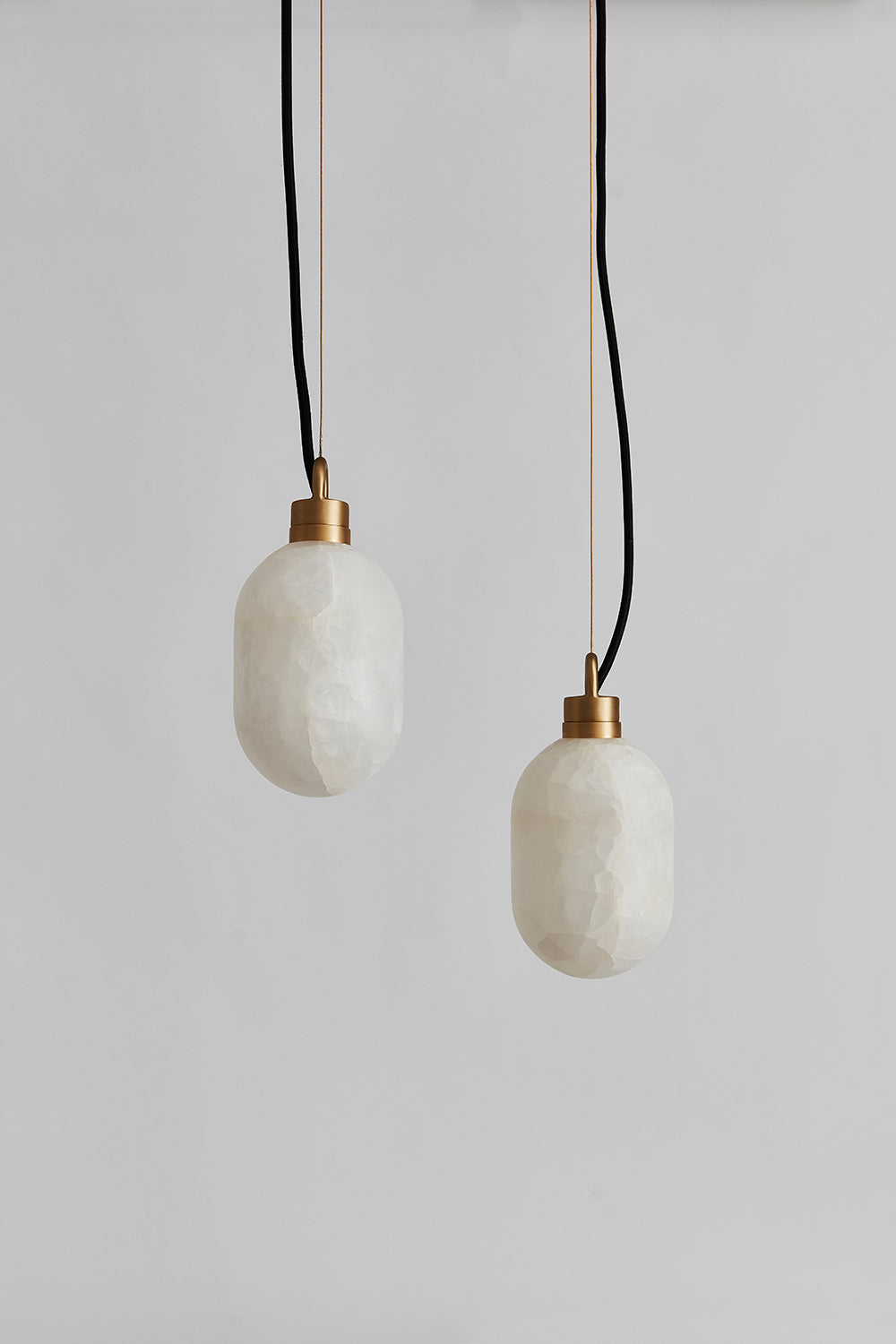 Clérachic Eclipse pendants hung as a pair at staggered heights, both stone shades unlit against a grey backdrop.