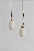 Clérachic Eclipse pendants hung as a pair at staggered heights, both stone shades unlit against a grey backdrop.