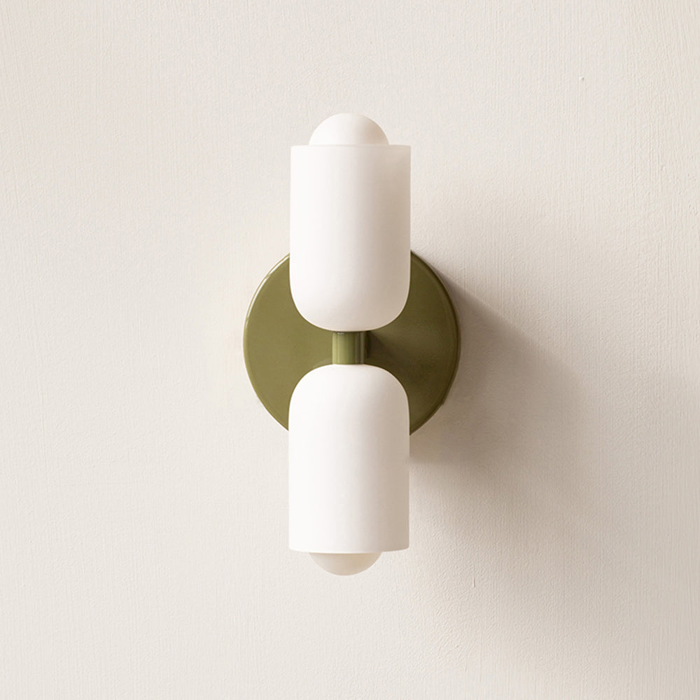 Clérachic opal wall sconce in muted green, olive backplate and short centre stem against a pale plaster wall.