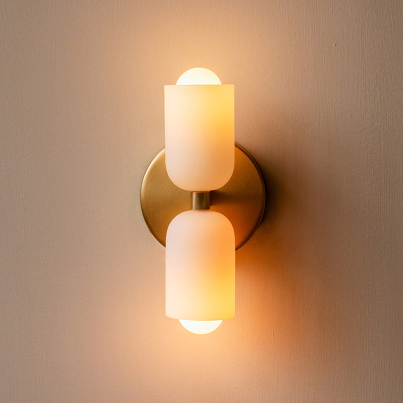 The Clérachic wall sconce lit in gold, warm light washing up the wall and down below from its two opal shades.