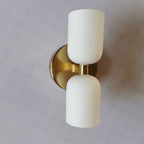 Close view of the Clérachic Up-and-Down Opal Wall Sconce in gold, brushed backplate and stem seen from below.