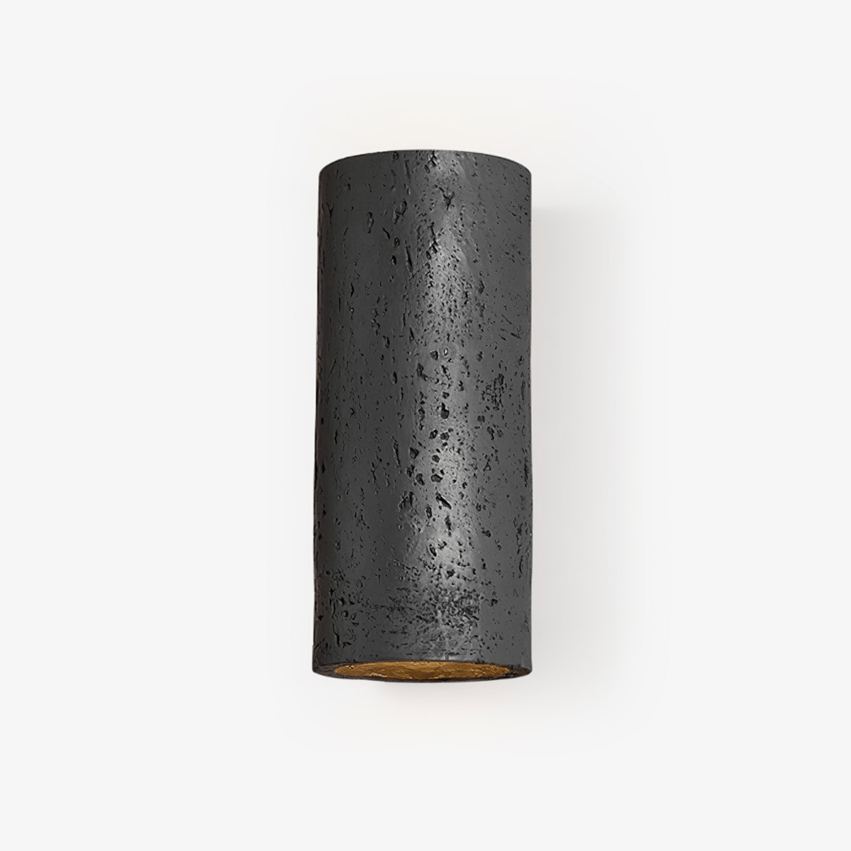 Black cylinder wall light with a pitted, stone-like surface and a warm gold glow inside the open end, on a pale backdrop; a Clérachic wall sconce.