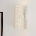 Close view of the cream cylinder's speckled surface and its round white wall plate with a screw; a Clérachic wall light.