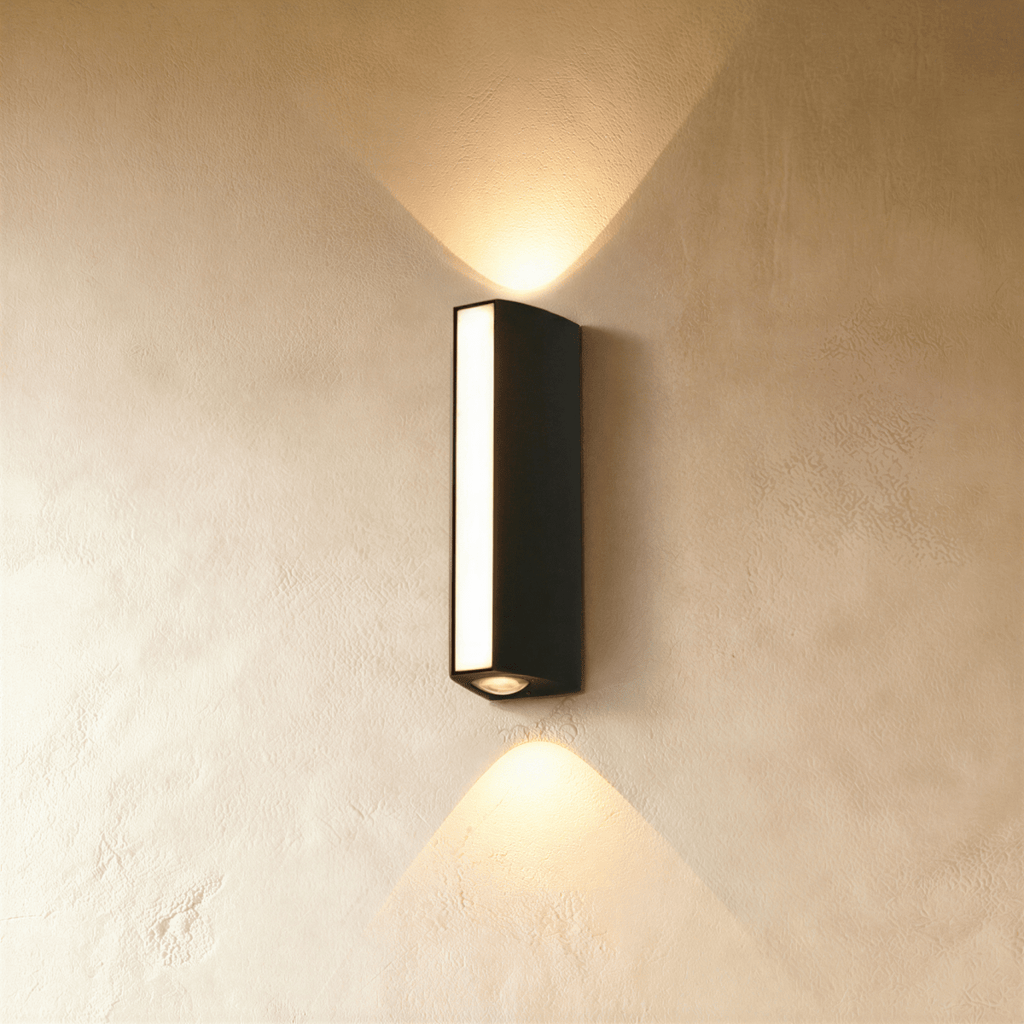 Clérachic slim matte black rectangular wall lamp with a frosted front strip, throwing warm beams up and down a limewash wall.