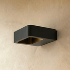 Clérachic square black wall light switched off, showing its brass-toned inner reflector on a warm plaster wall.