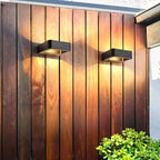 Pair of Clérachic black wall lights on a vertical timber fence, each washing the grain with warm light above and below.