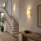 Clérachic wall lights at a staircase landing, a nearer one above a wooden console with a bowl and books, and one further up.