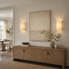 Pair of Clérachic wall lights either side of a large framed print above an oak sideboard, with a dining room beyond.