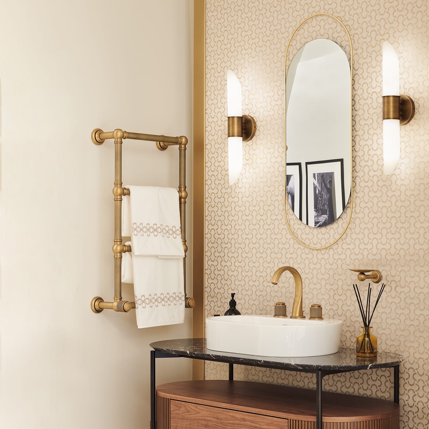 A pair of Clérachic Up-Down Wall Sconces lit either side of an oval mirror above a marble-top bathroom vanity.