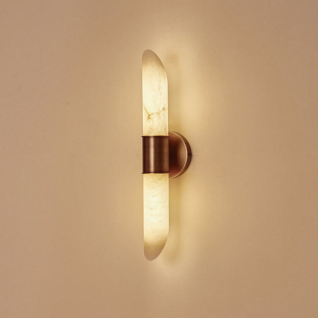 Clérachic Up-Down Wall Sconce switched on, the alabaster glowing honey-amber and washing light up and down a plaster wall.