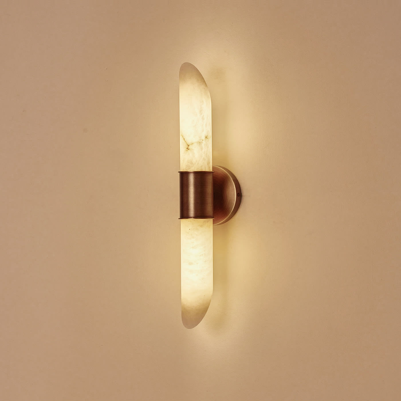 Clérachic Up-Down Wall Sconce switched on, the alabaster glowing honey-amber and washing light up and down a plaster wall.