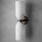 Clérachic up-down wall sconce seen straight on, its twin alabaster cups joined by a brass band on grey limewash.