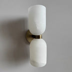 Clérachic alabaster wall sconce photographed from below, brass band catching the daylight while the stone reads cool white.