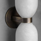 Detail of the Clérachic sconce's brass wall plate and the flat band that wraps the alabaster waist, seen unlit up close.