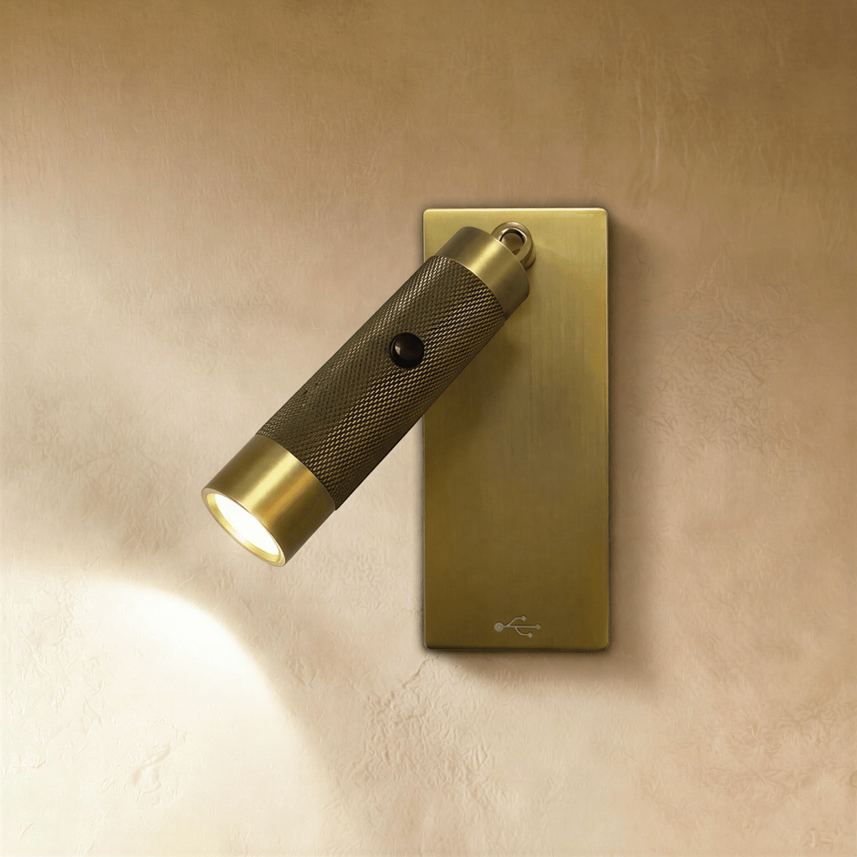Clérachic wall reading light with a knurled dark bronze cylinder on a brushed brass rectangular plate, its beam lit on plaster.