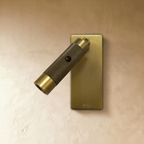 Clérachic wall reading light, unlit, with a dark knurled bronze barrel and brass cap on a brushed rectangular plate and USB mark.
