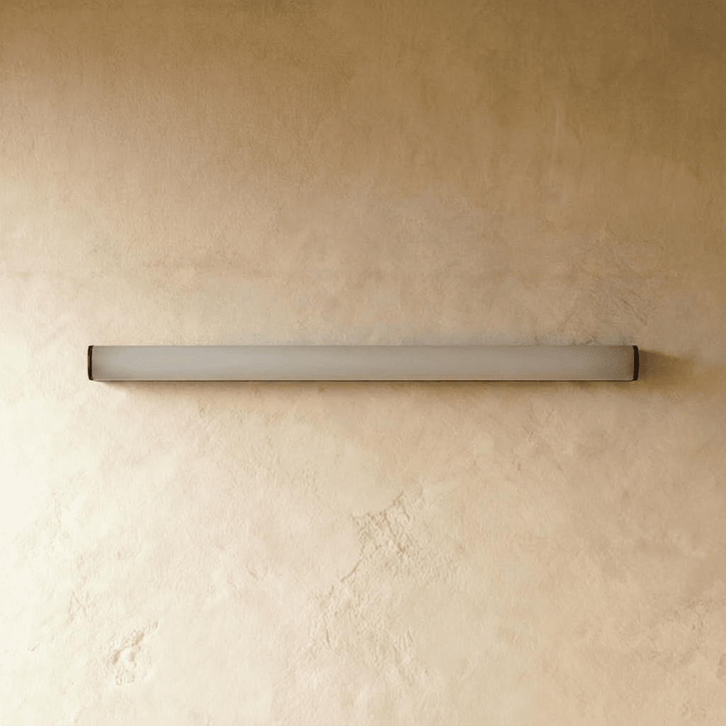 Clérachic slim linear wall light switched off, a frosted white diffuser tube with black end caps on warm plaster.
