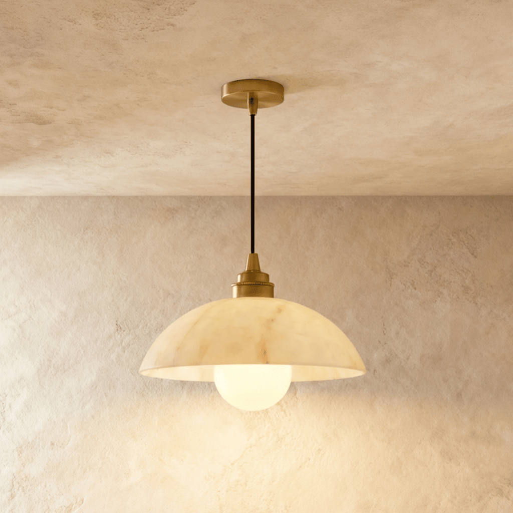 Clérachic alabaster dome pendant with a gold fitting and an opal glass globe bulb, glowing warm against limewash.