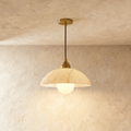 Clérachic pendant with a wide, softly veined alabaster dome and gold fitting, its opal globe bulb lit on plaster.