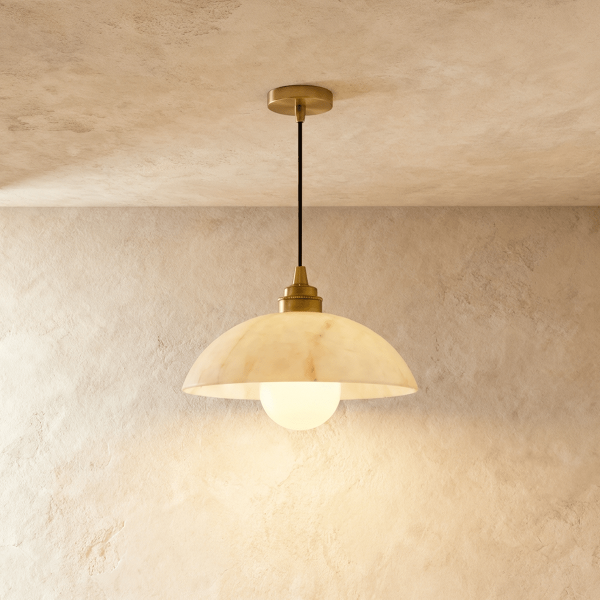 Clérachic pendant with a wide, softly veined alabaster dome and gold fitting, its opal globe bulb lit on plaster.