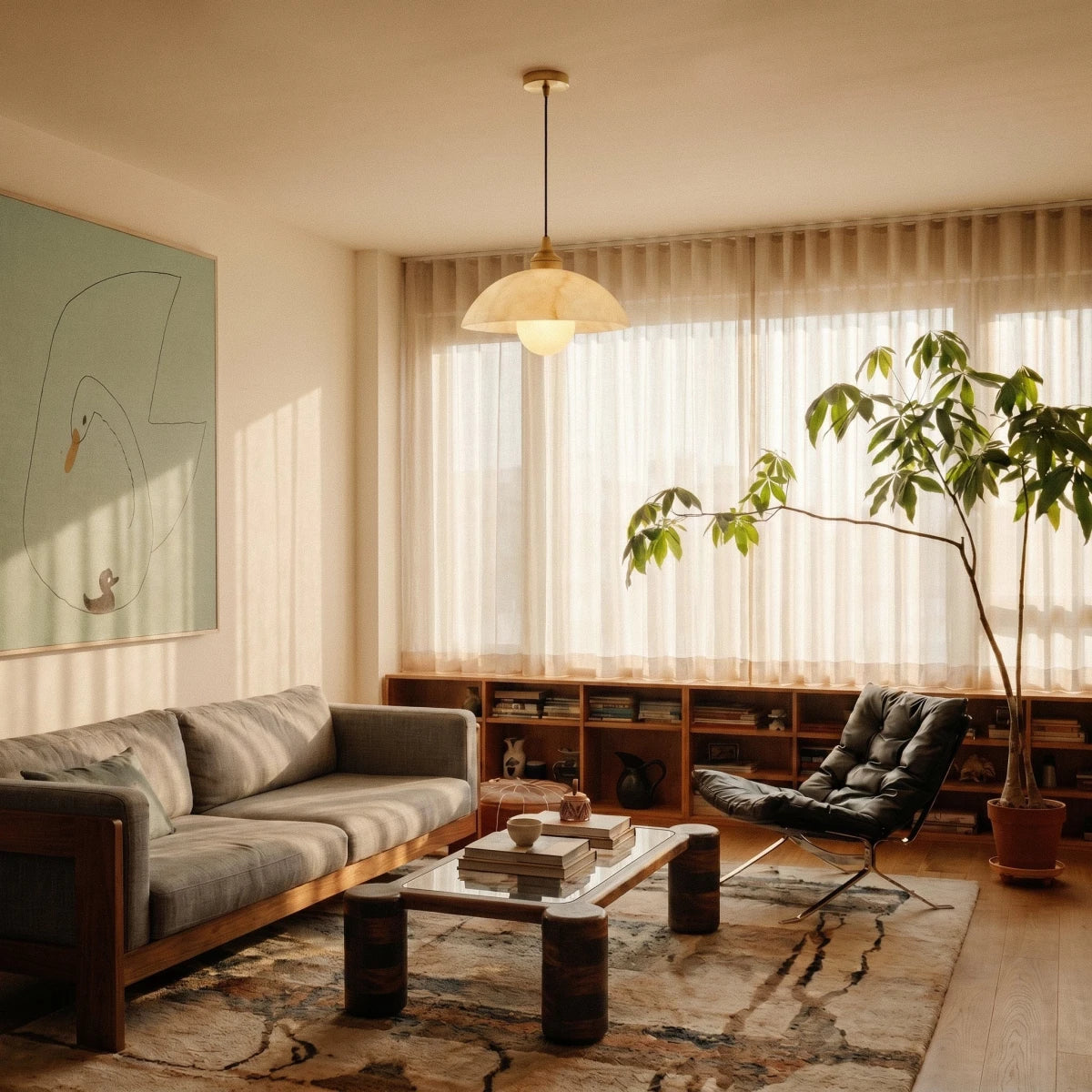 Clérachic alabaster dome pendant hanging in a bright living room, with a sofa, low shelving, a tall plant and sheer curtains.