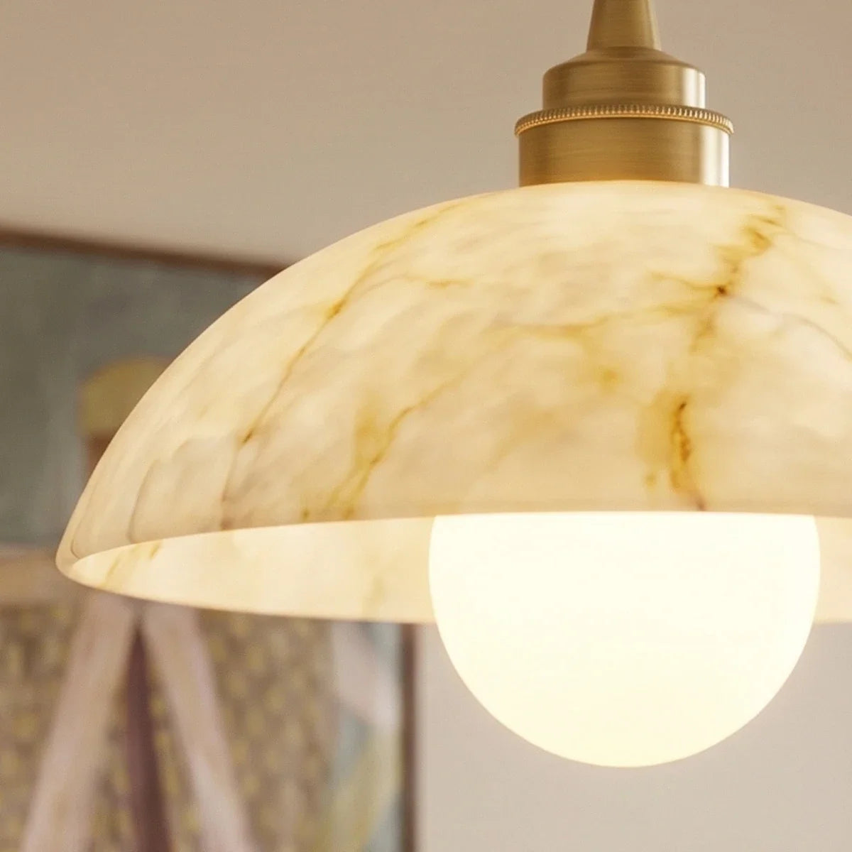 Close detail of a Clérachic alabaster dome with honey-gold veining, a knurled gold collar and a lit opal globe bulb.