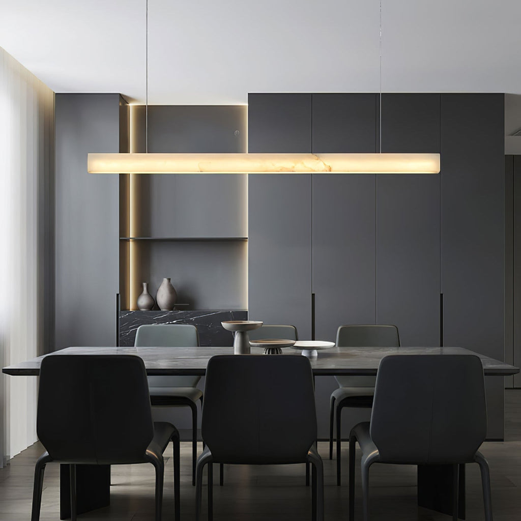 The Clérachic Velmore pendant lighting a dark dining table with black upholstered chairs.