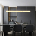The Clérachic Velmore pendant lighting a dark dining table with black upholstered chairs.