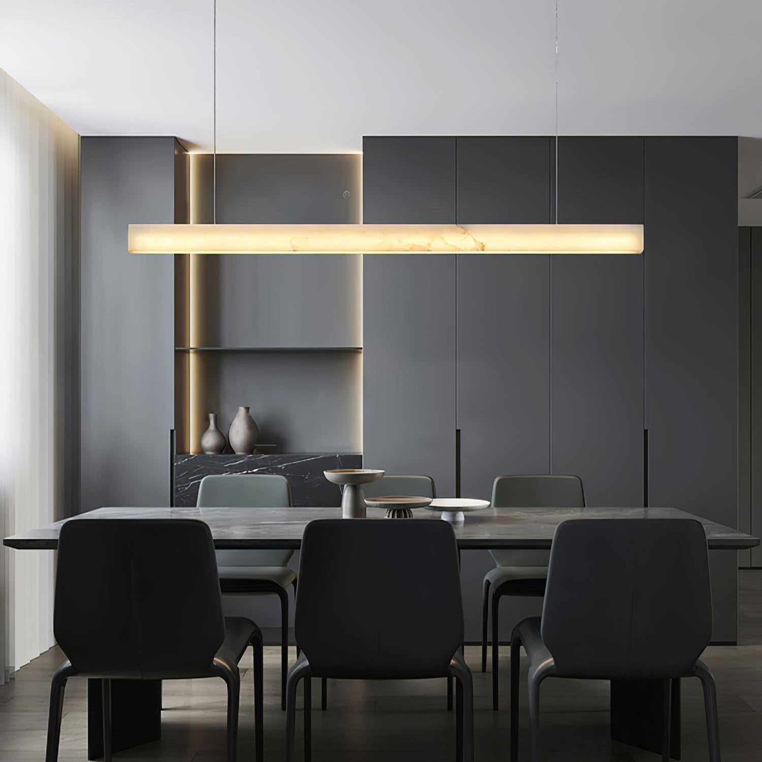 The Clérachic Velmore pendant lighting a dark dining table with black upholstered chairs.