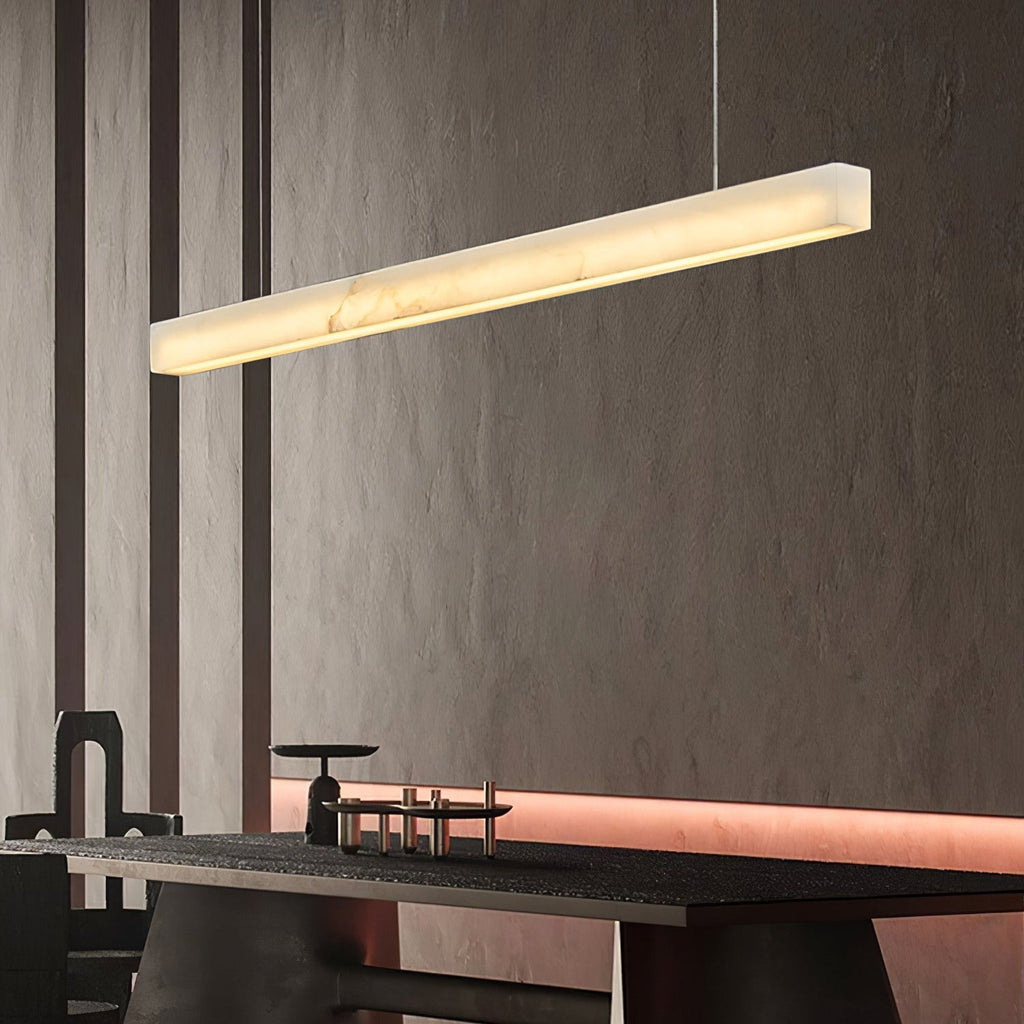 Clérachic Velmore pendant glowing above a counter against a textured dark stone wall.